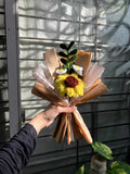 Hand holding a small bouquet of flowers with a textured background
