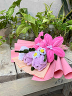 Bouquet of pink and purple flowers on a wooden surface with plants in the background