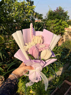 Hand holding a bouquet of flowers with greenery in the background