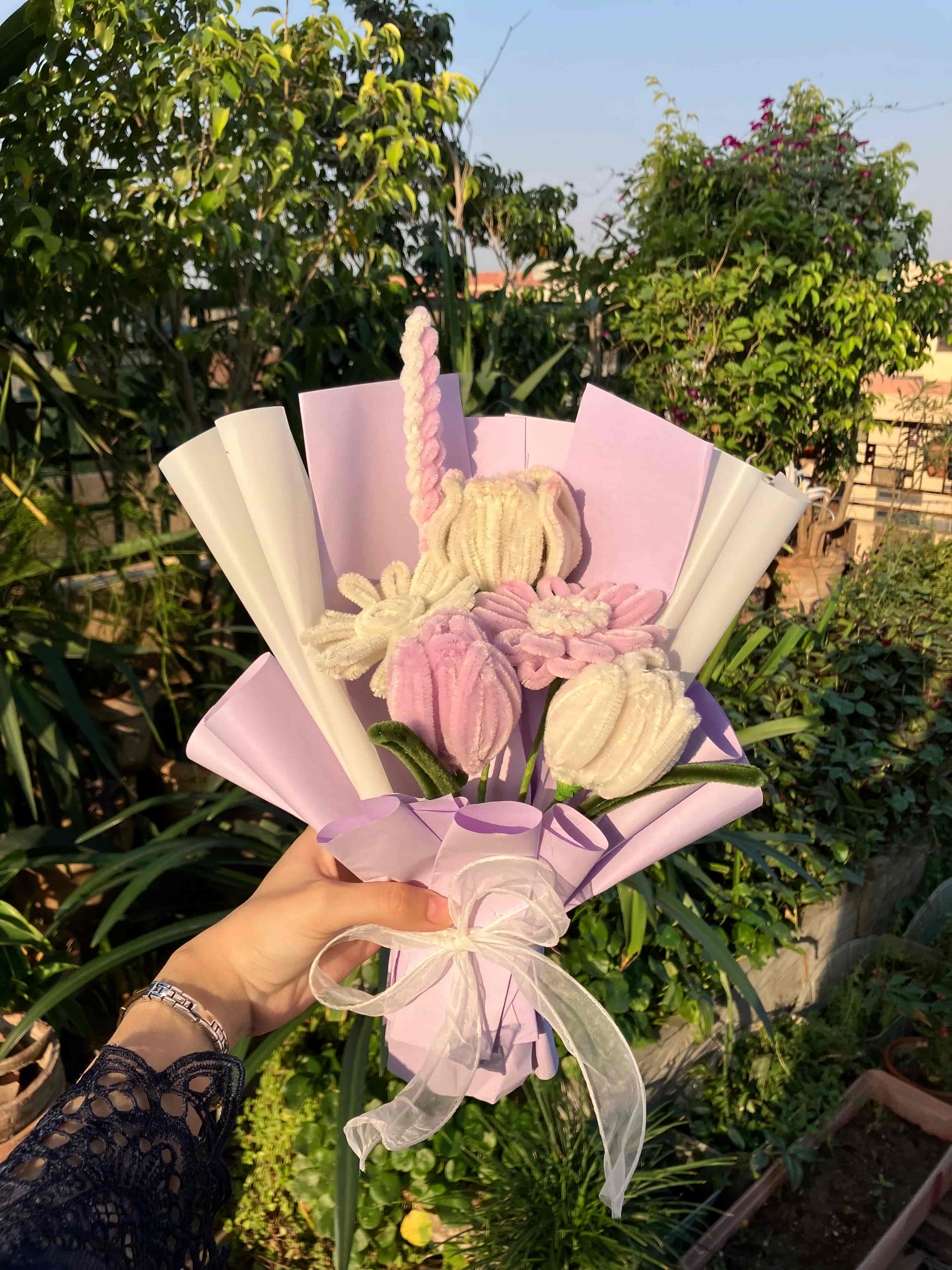 Hand holding a bouquet of flowers with greenery in the background