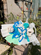 Decorative wreath with blue and white flowers on a stand outdoors