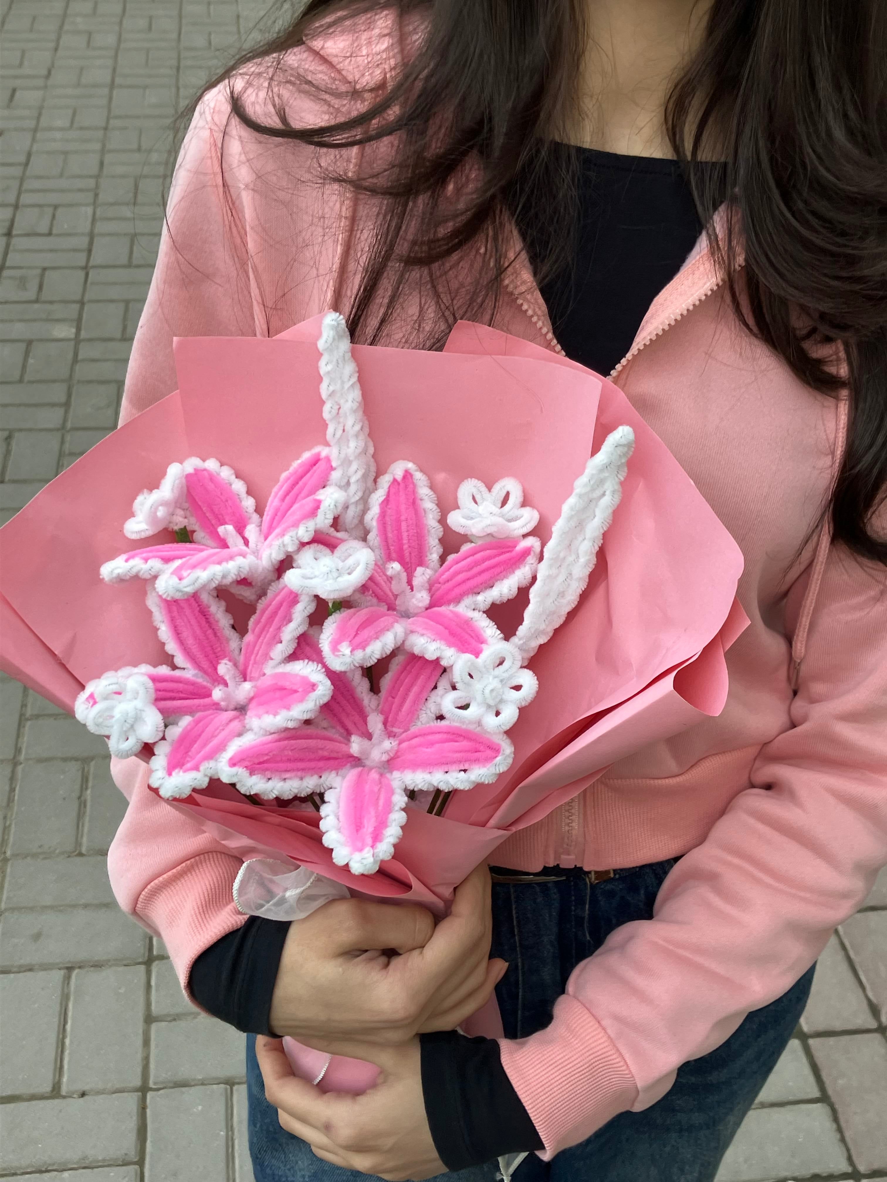 Person holding a bouquet of pink flowers with white accents