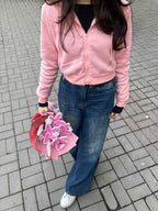 Person holding a pink flower arrangement on a tiled pavement