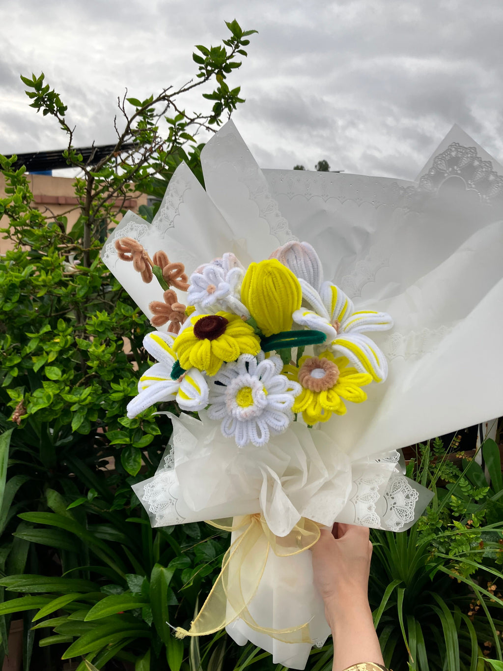 Bouquet of flowers held by a person with greenery in the background
