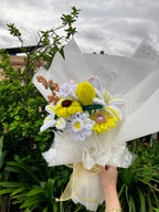 Bouquet of flowers held by a person with greenery in the background