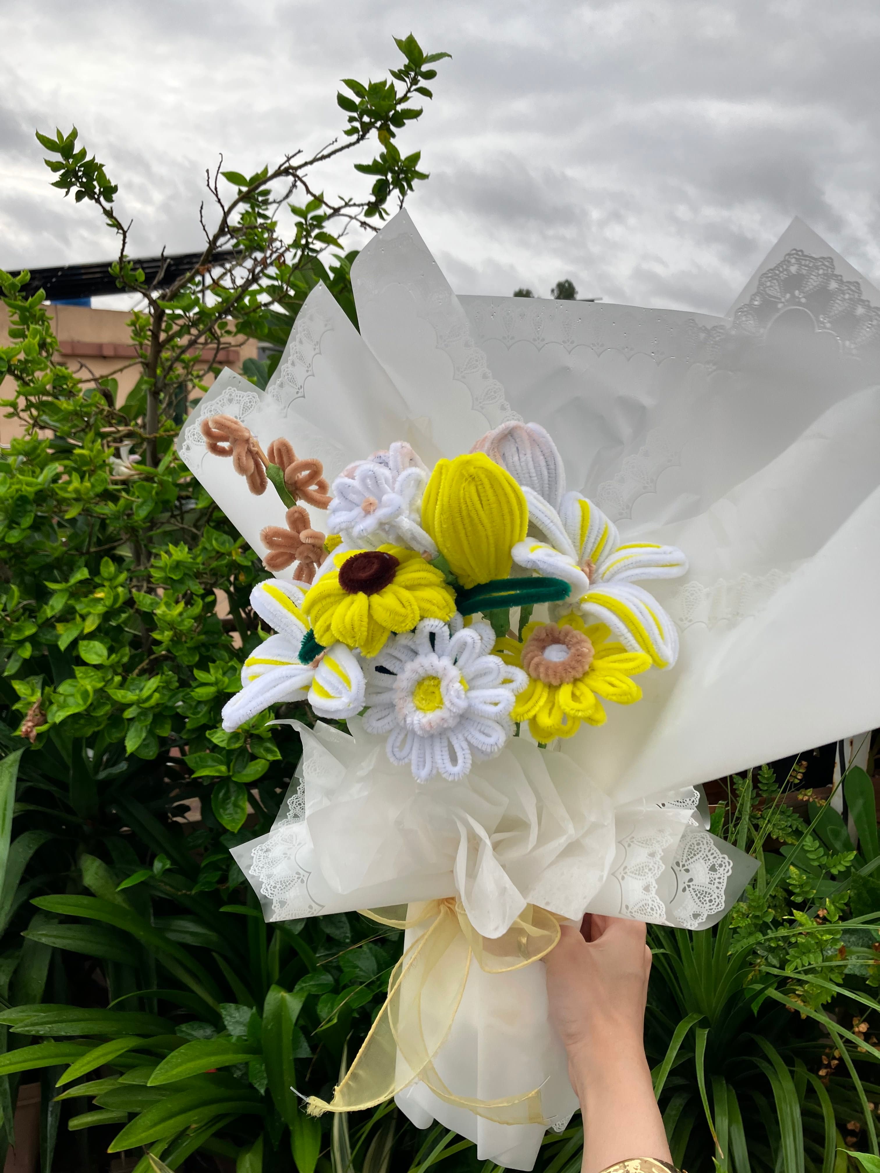 Bouquet of flowers held by a person with greenery in the background