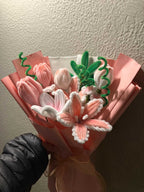 Bouquet of pink and white flowers with green leaves on a textured surface.