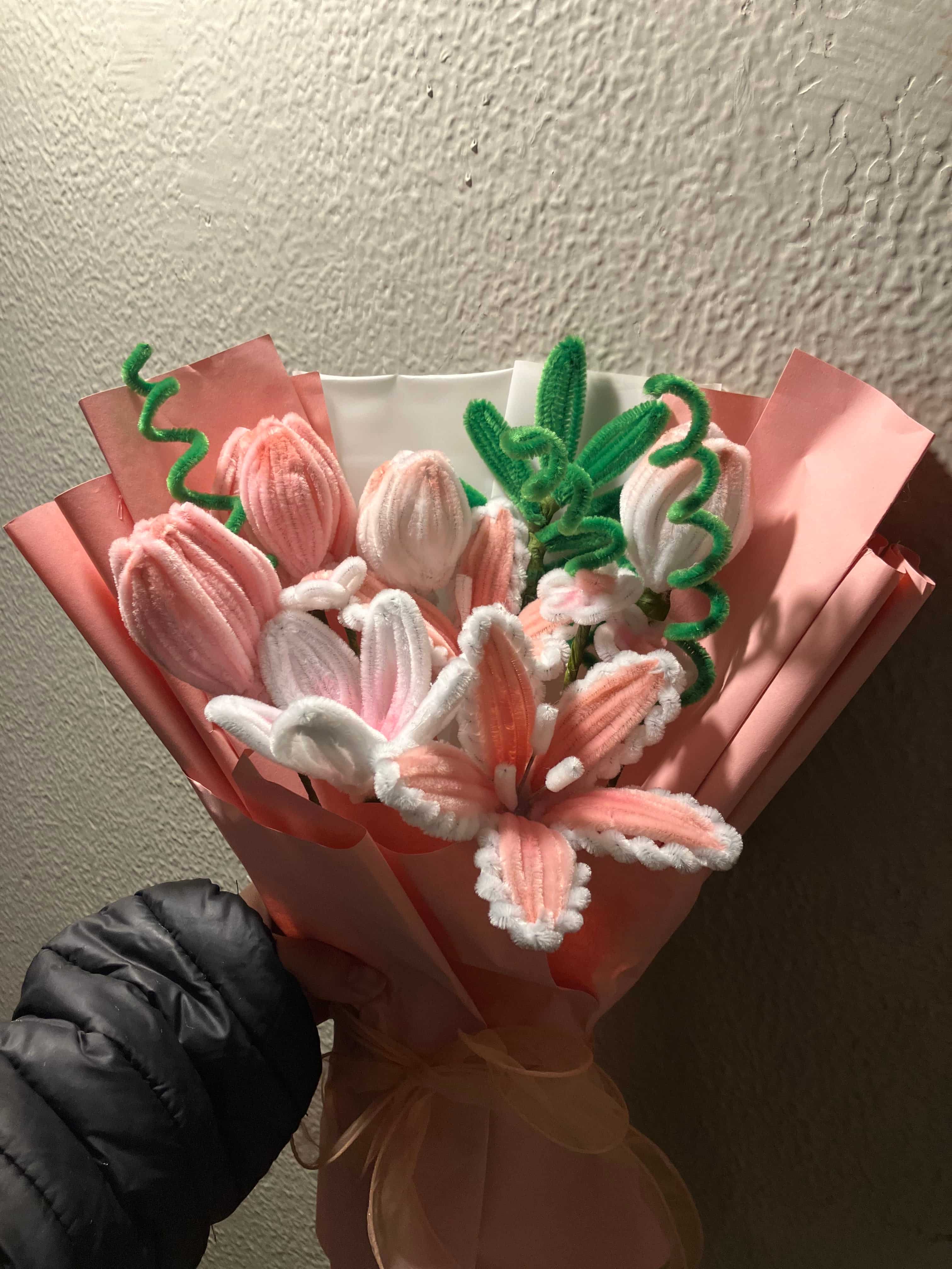 Bouquet of pink and white flowers with green leaves on a textured surface.