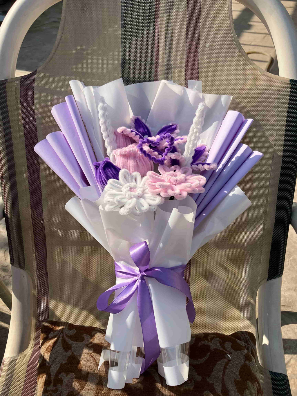 Bouquet of flowers with purple and white ribbons on a chair