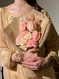 Person holding a bouquet of pink flowers with gold accents