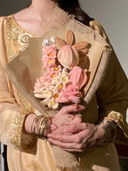 Person holding a bouquet of pink flowers with gold accents