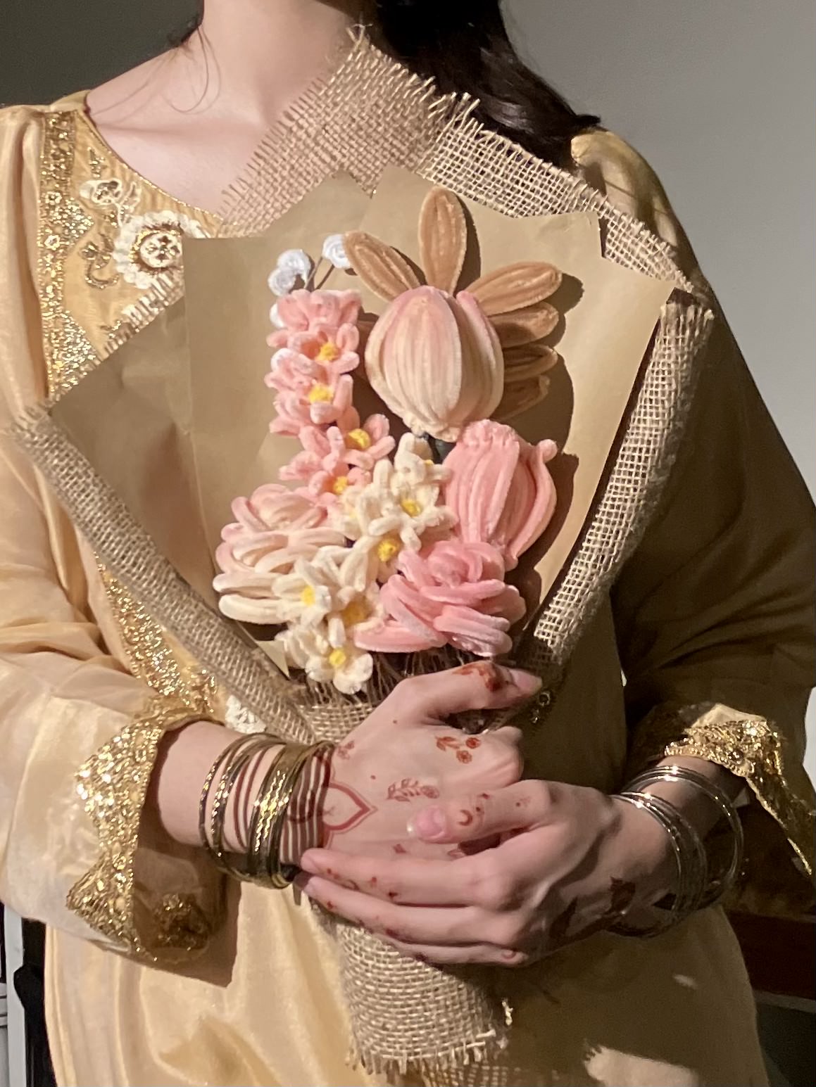 Person holding a bouquet of pink flowers with gold accents
