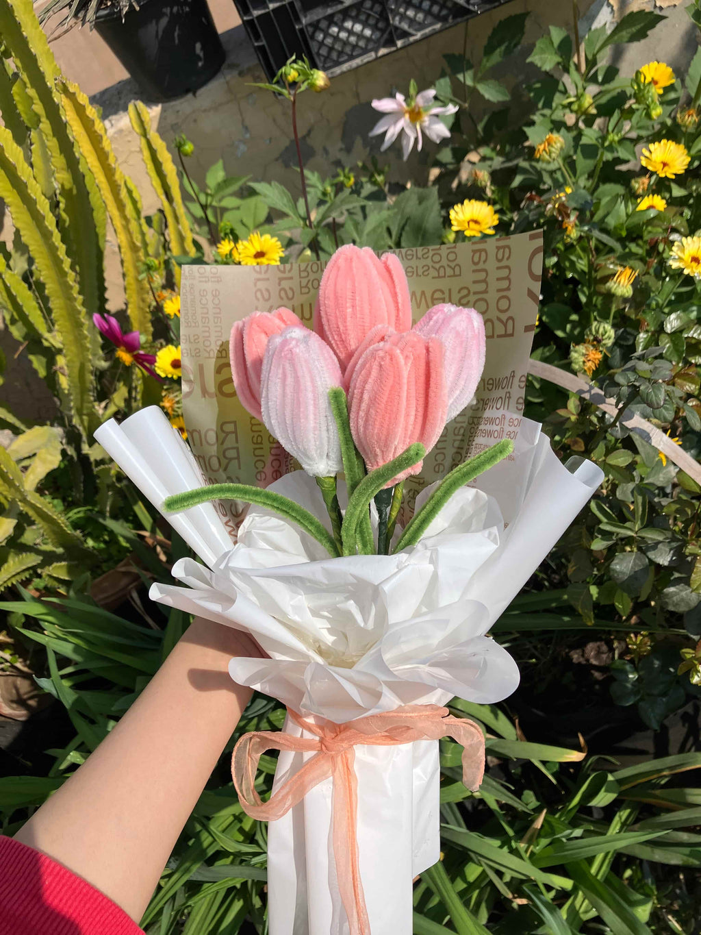 Bouquet of pink and white tulips held by a person with greenery in the background
