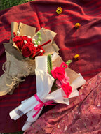 Bouquet of flowers and gift wrapped items on a red fabric background
