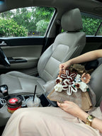 Person sitting in a car with flowers and a box, holding a cup.