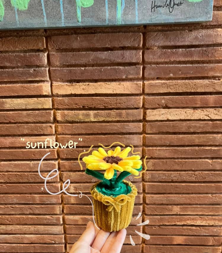 Knitted sunflower held against a wooden background with 'sunflower' text.