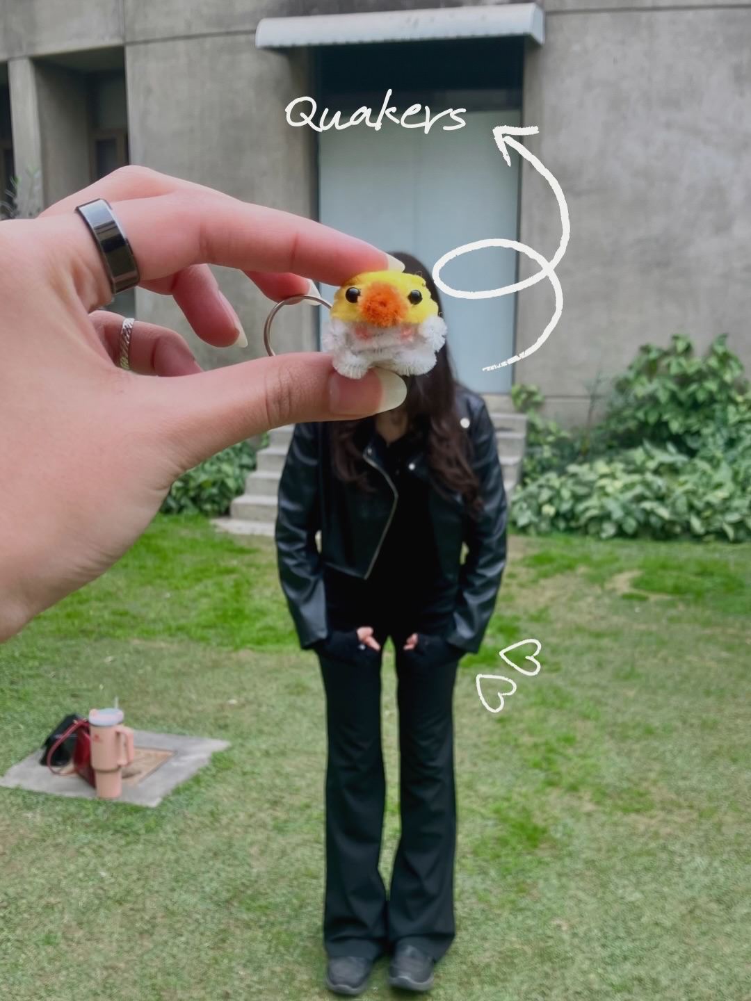 Person holding a plush toy with 'Quakers' text, standing outdoors.