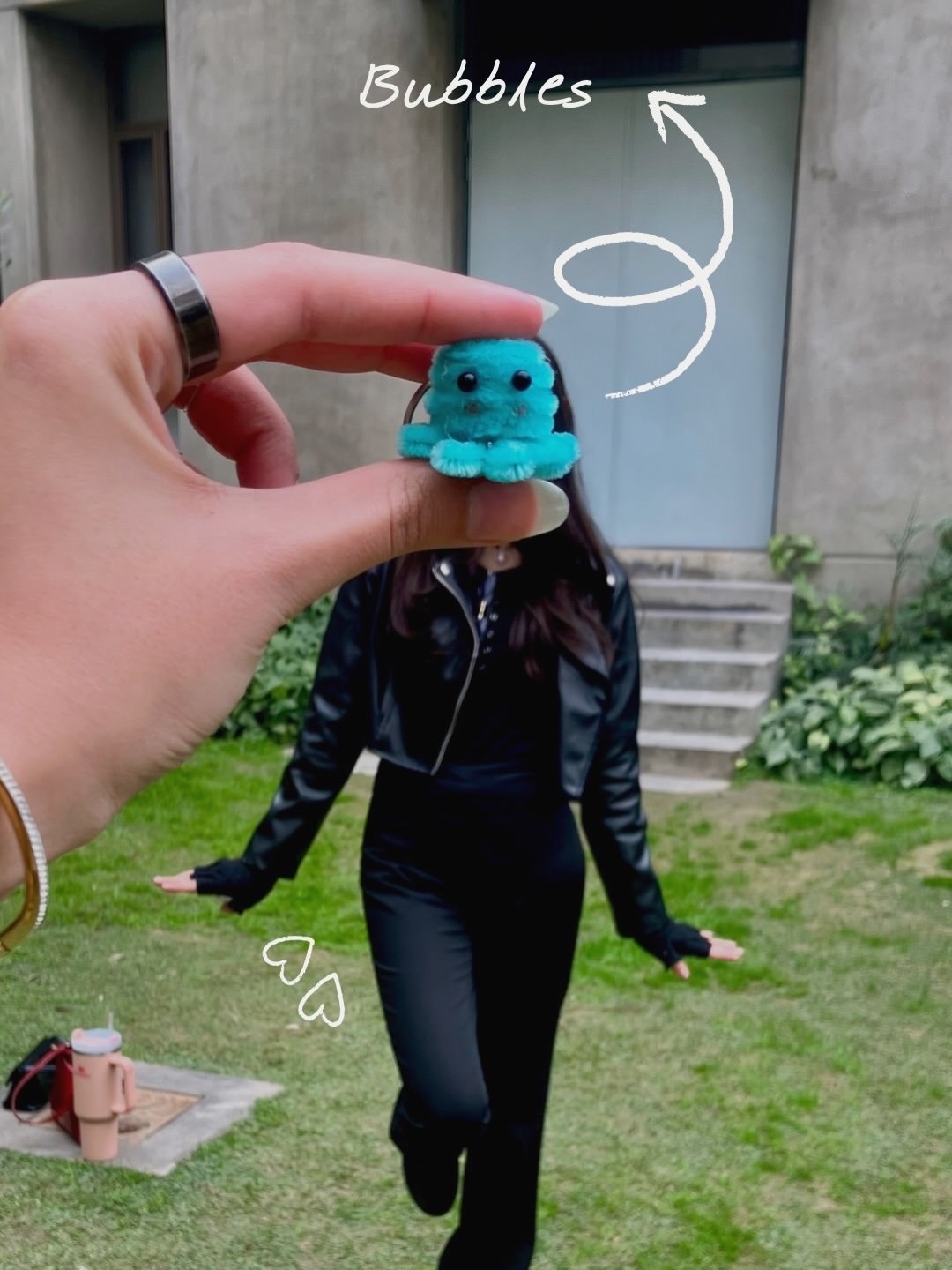 Person holding a small blue creature toy with 'Bubbles' text, standing outdoors.
