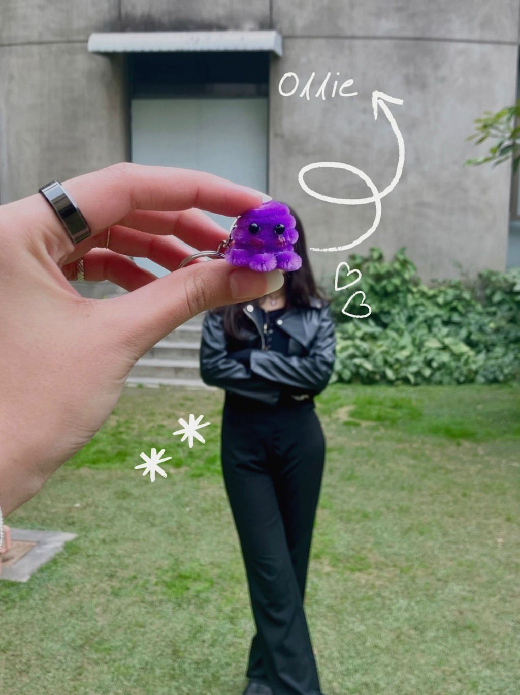 Hand holding a purple keychain with a person in the background