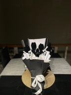 Bouquet of black tulips with white ribbons on a black leather chair.