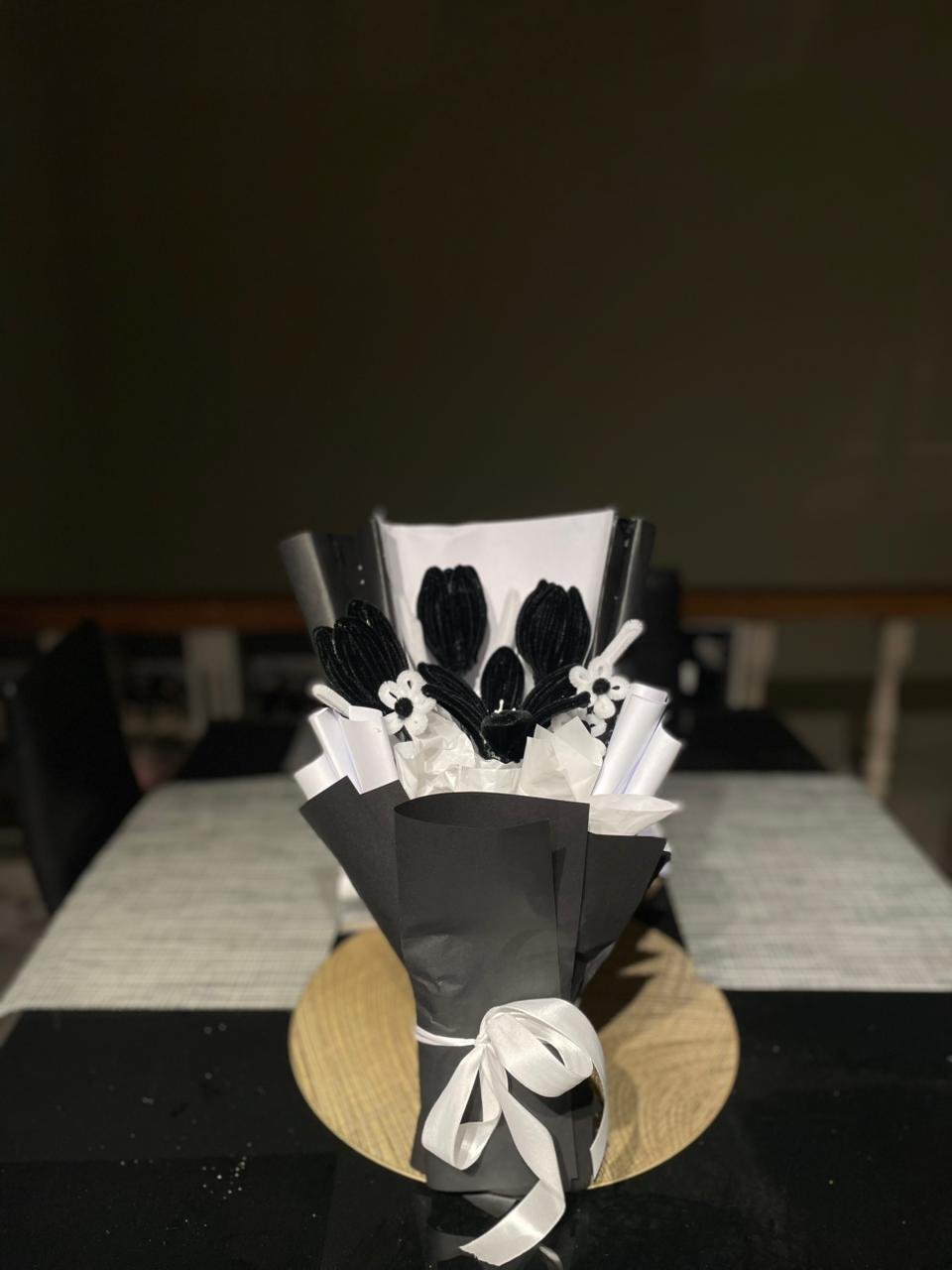 Bouquet of black tulips with white ribbons on a black leather chair.