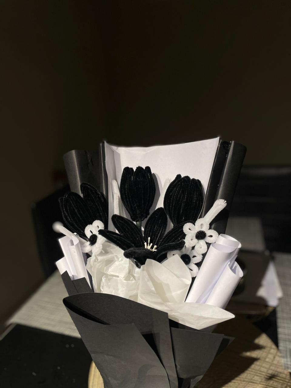 Bouquet of black and white flowers on a dark surface