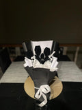 Decorative black and white flower arrangement on a table with a dark background