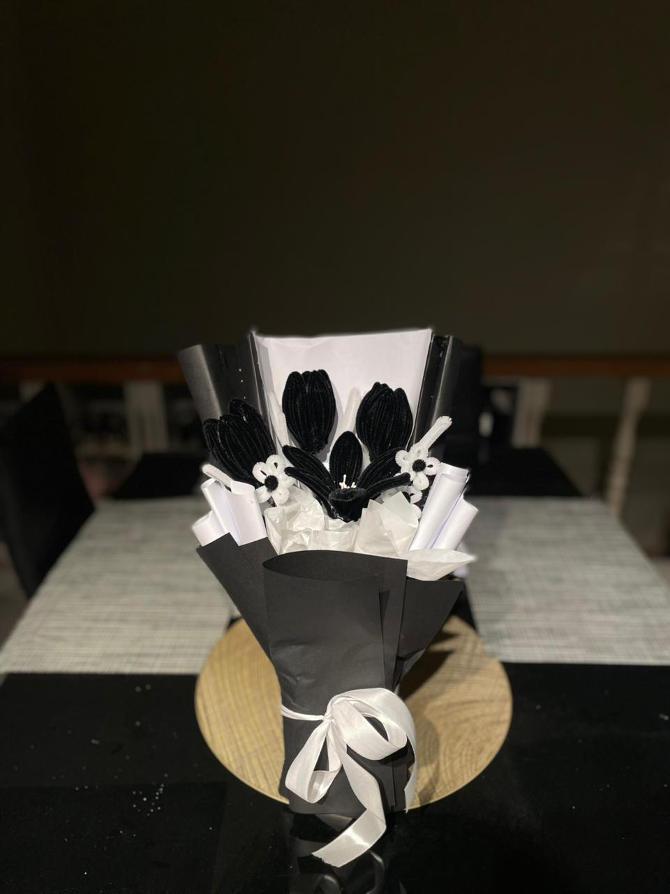 Decorative black and white flower arrangement on a table with a dark background