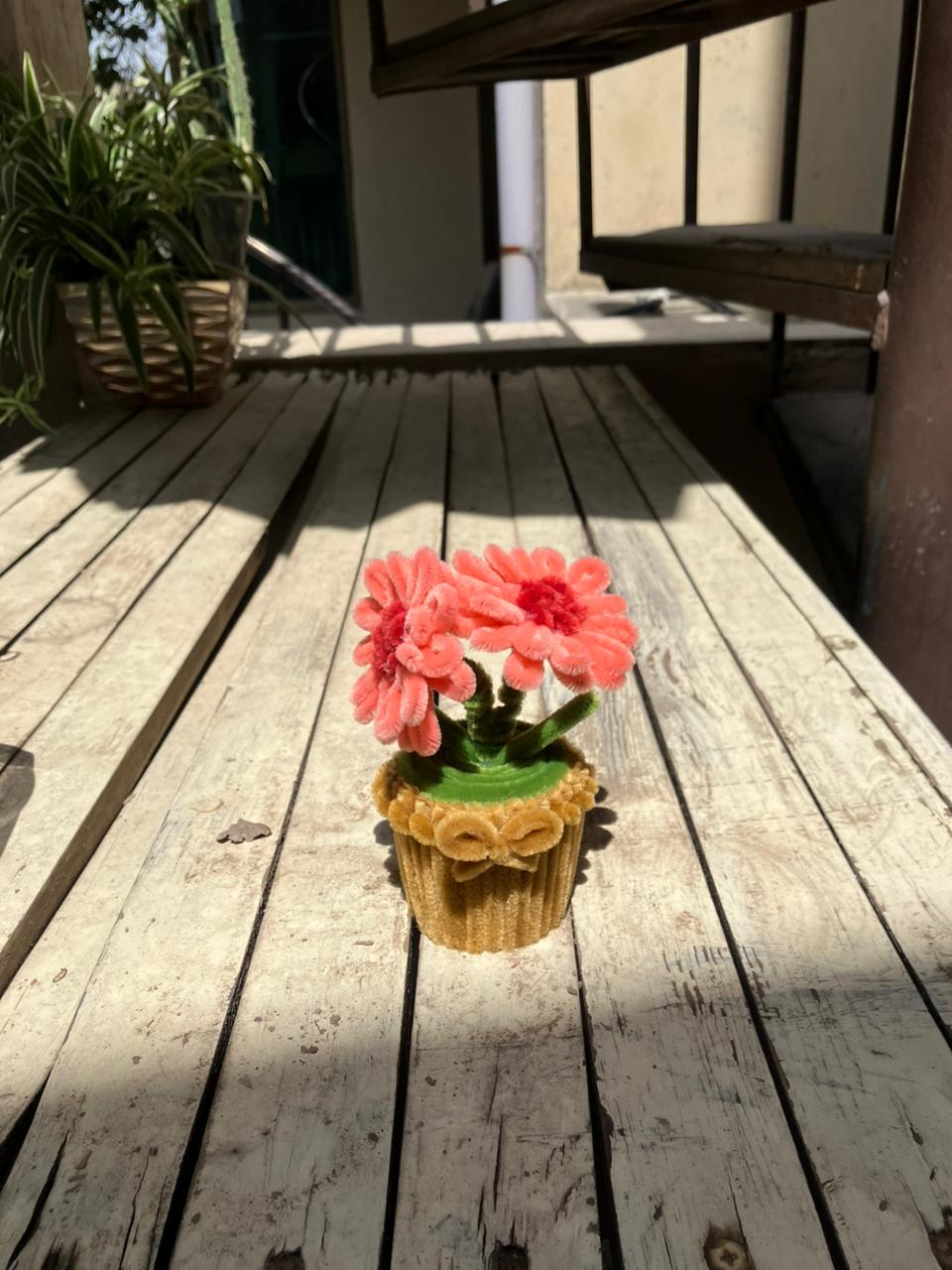 Pink flowers in a decorative pot on a wooden deck