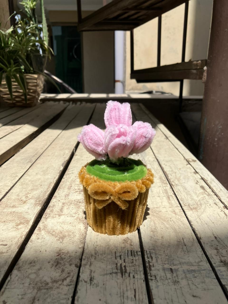 Cupcake with pink flower on a wooden surface