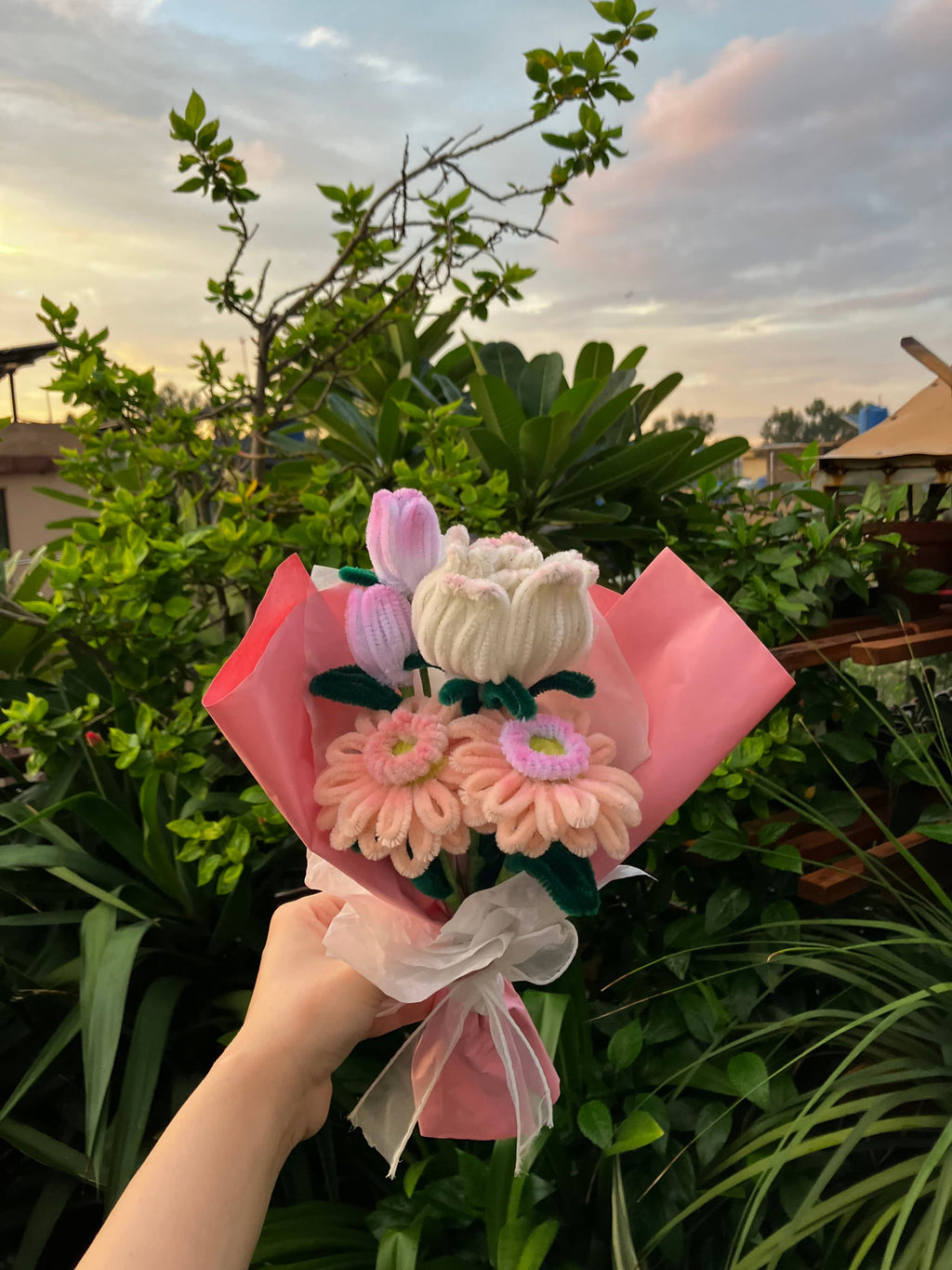 Bouquet of flowers held by a hand with a scenic background
