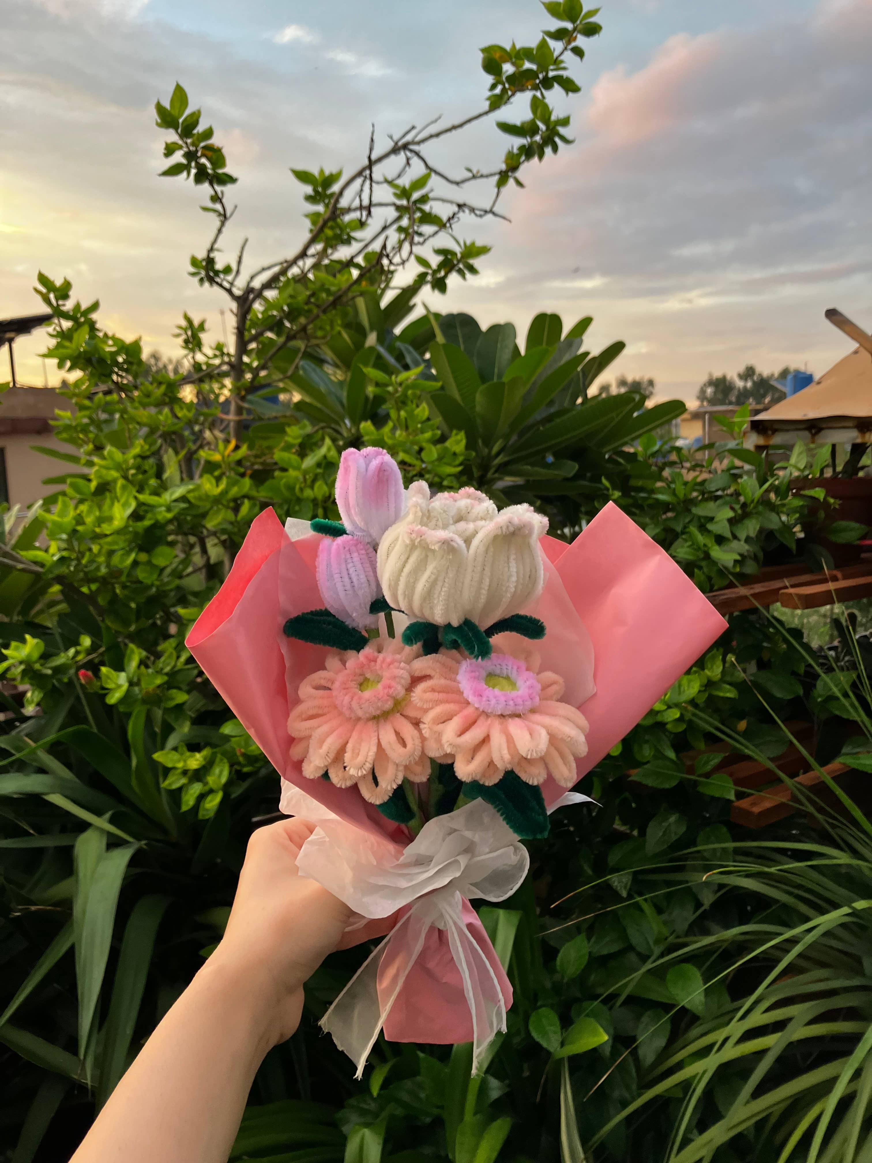 Bouquet of flowers held by a hand with a scenic background