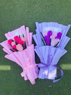 Two bouquets of artificial tulips, one pink and one purple, on a green grass background.