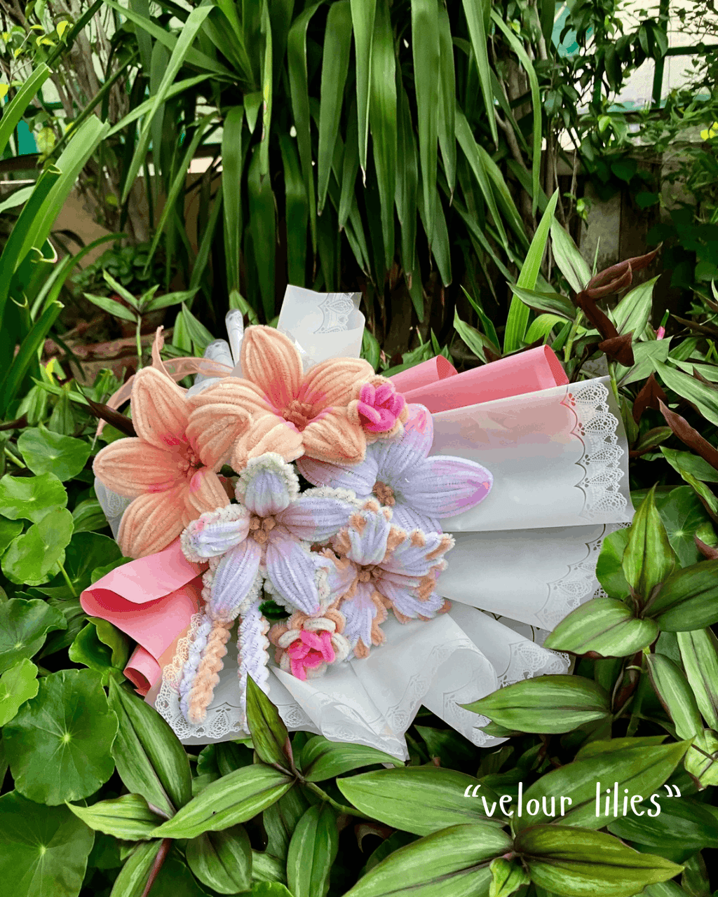 Bouquet of velour lilies with pink and white ribbons on a green leafy background