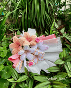 Bouquet of velour lilies with pink and white ribbons on a green leafy background