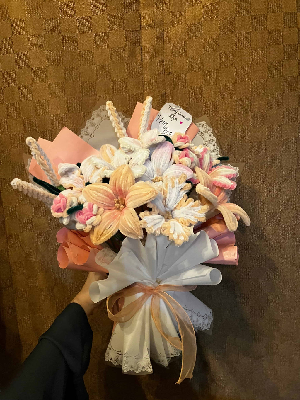 Bouquet of flowers held by a hand on a textured brown background