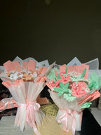 Bouquets of cookies wrapped in pink and white paper with ribbons on a dark background