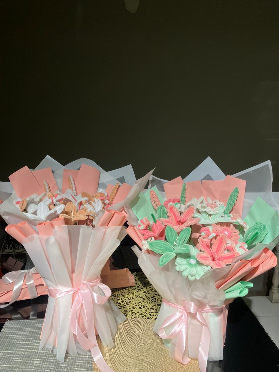 Bouquets of cookies wrapped in pink and white paper with ribbons on a dark background