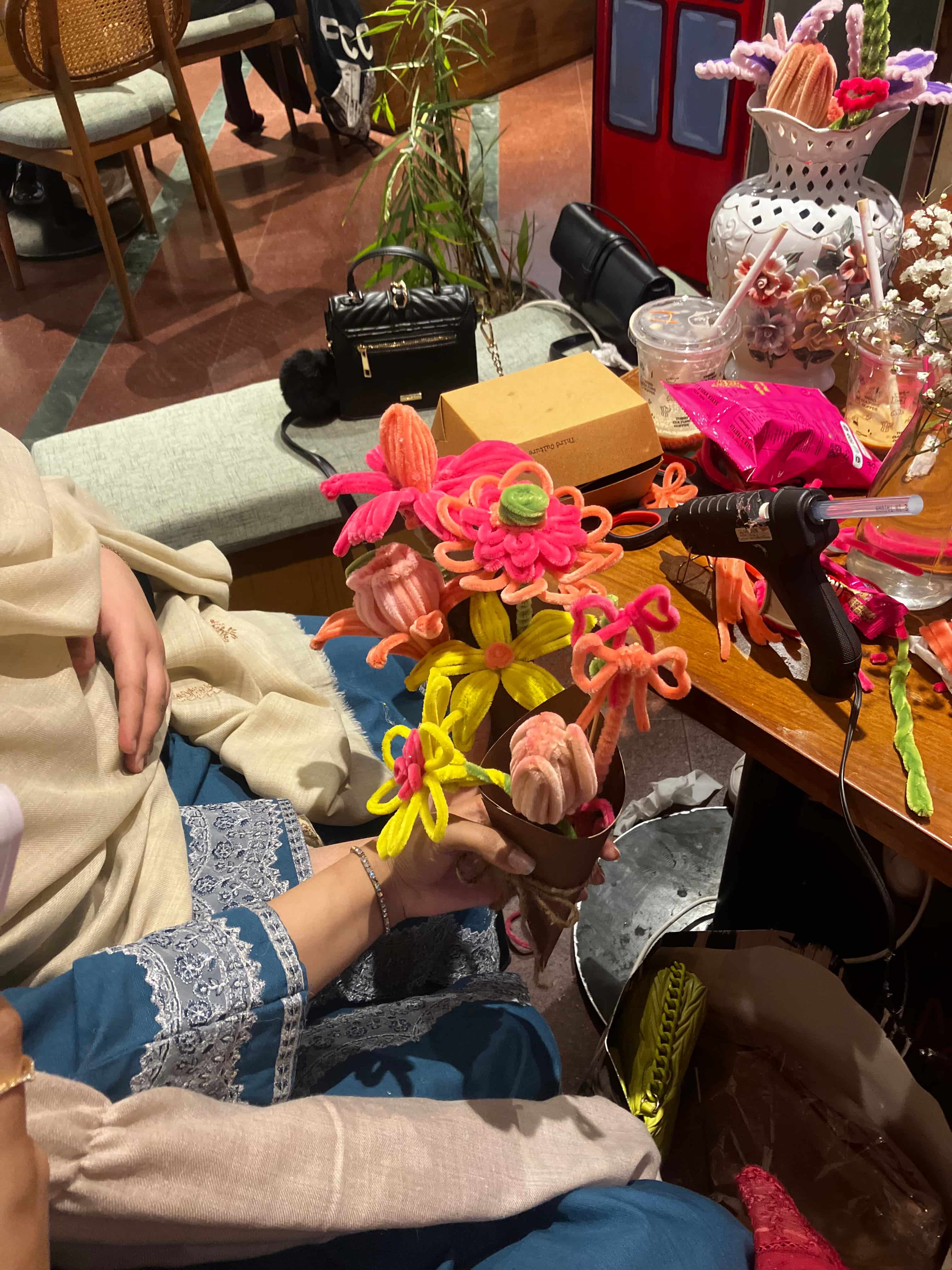 Colorful flower-shaped objects on a table with a person sitting nearby.