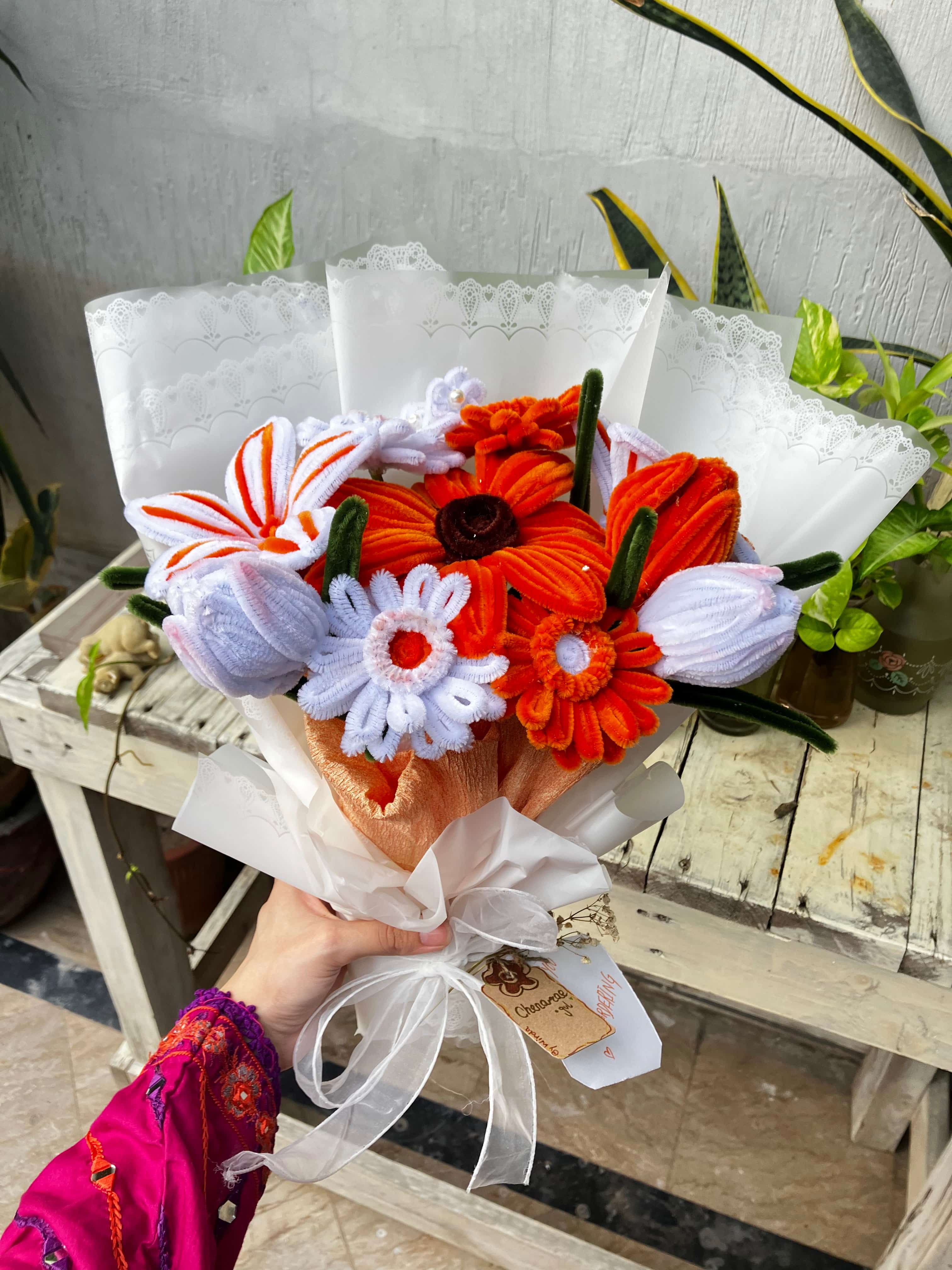 Bouquet of flowers with orange and white colors held by a person wearing a colorful jacket.