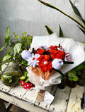 Bouquet of flowers with decorative elements on a wooden table with plants.