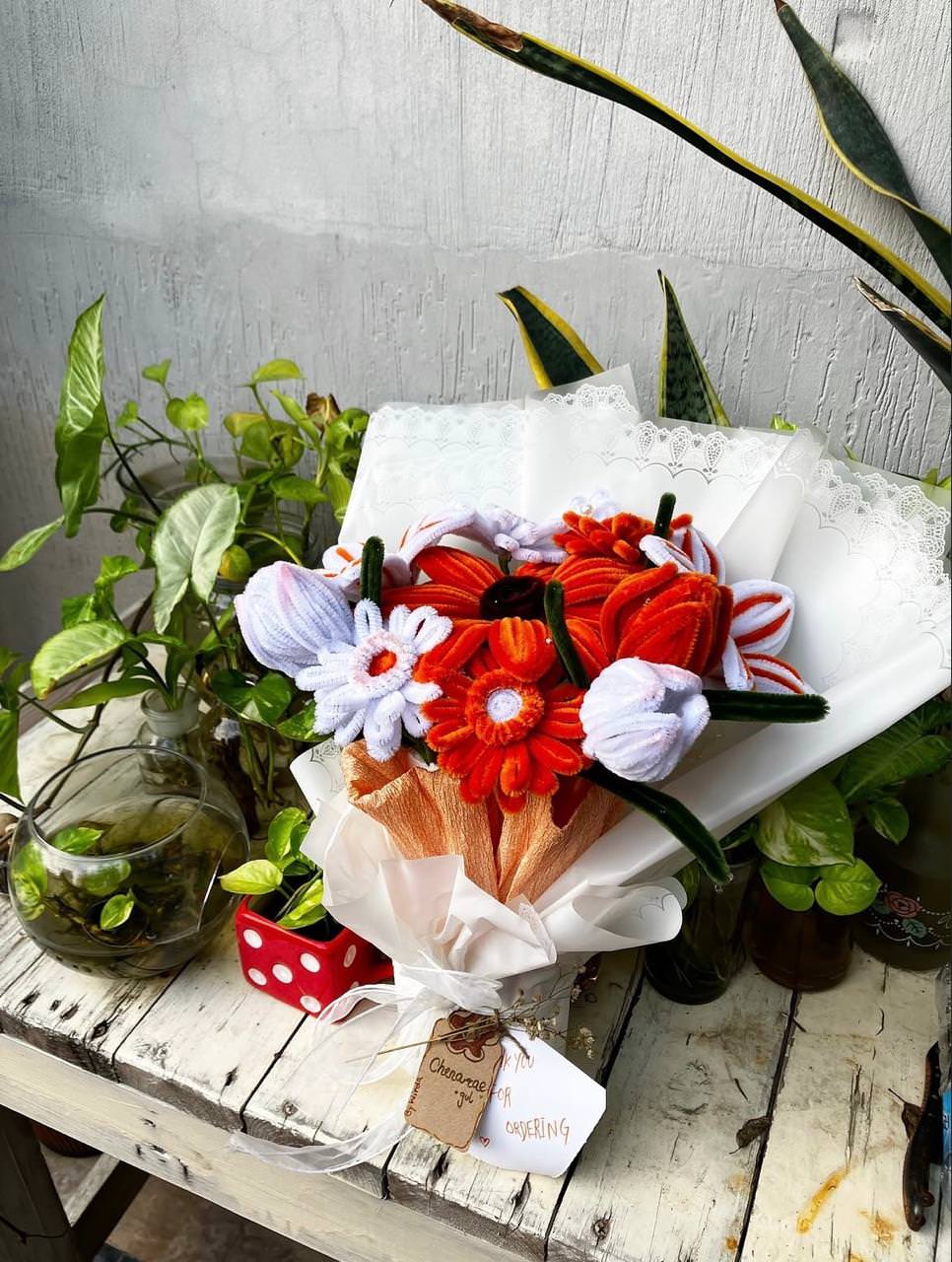 Bouquet of flowers with decorative elements on a wooden table with plants.