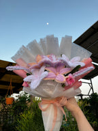 Decorative headband with flowers and ribbons held against a clear sky.